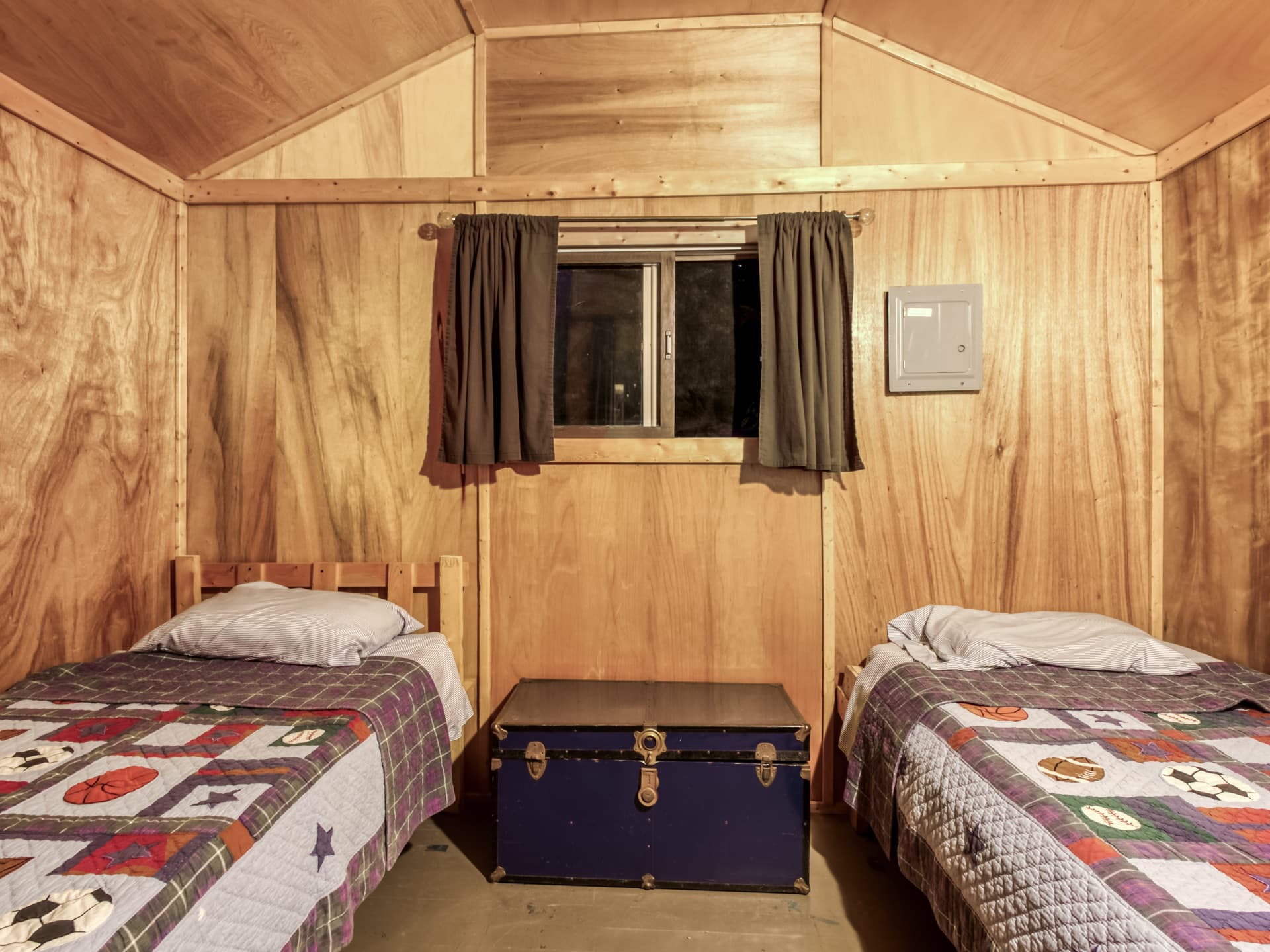 Cabin bedroom with two single beds and plywood walls