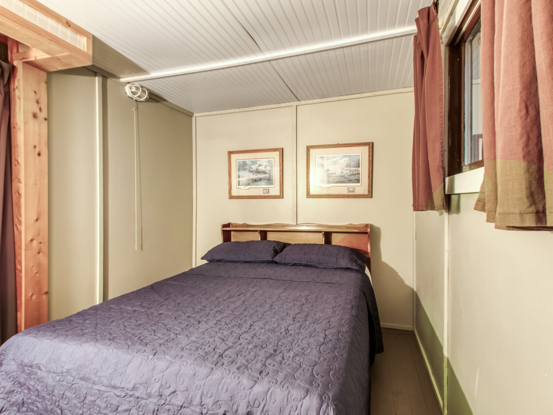 Cabin bedroom with a double bed, wood trim, and curtains
