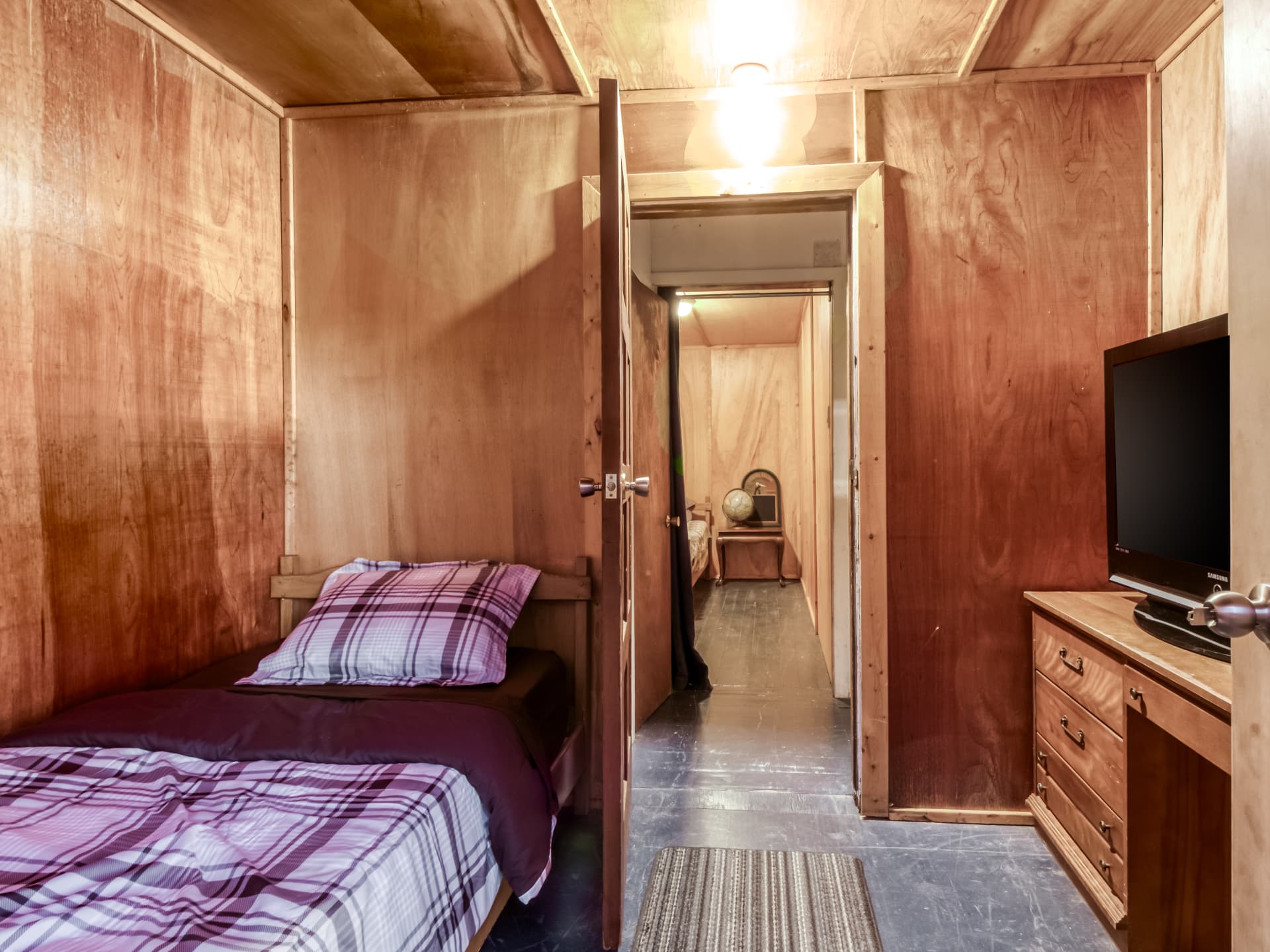 Cabin bedroom with a single bed and an adjoining room beyond